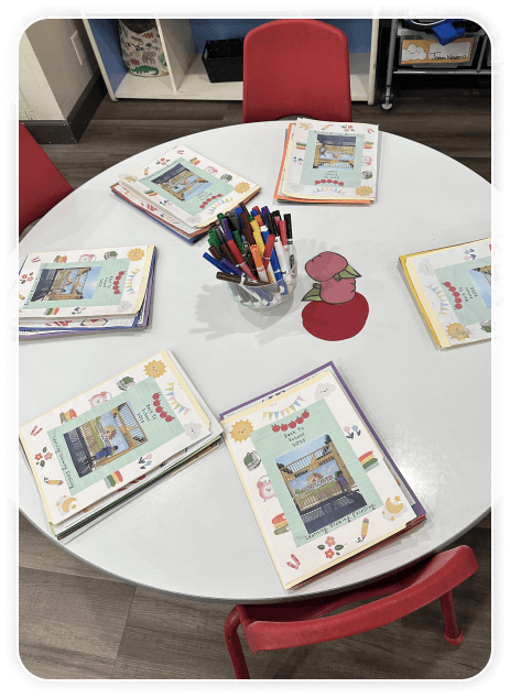 Round table in a preschool classroom displaying children's art and learning projects from the school year.